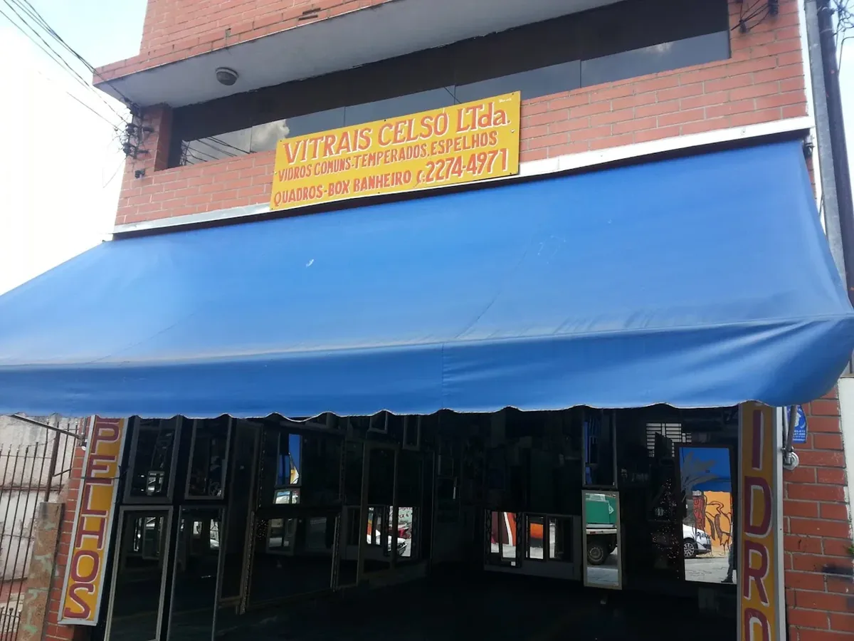 Fachada da loja Vitrais Celso Ltda. na Rua Alencar Araripe, no Sacomã: placa amarela, toldo azul e vitrine com espelhos e vidros